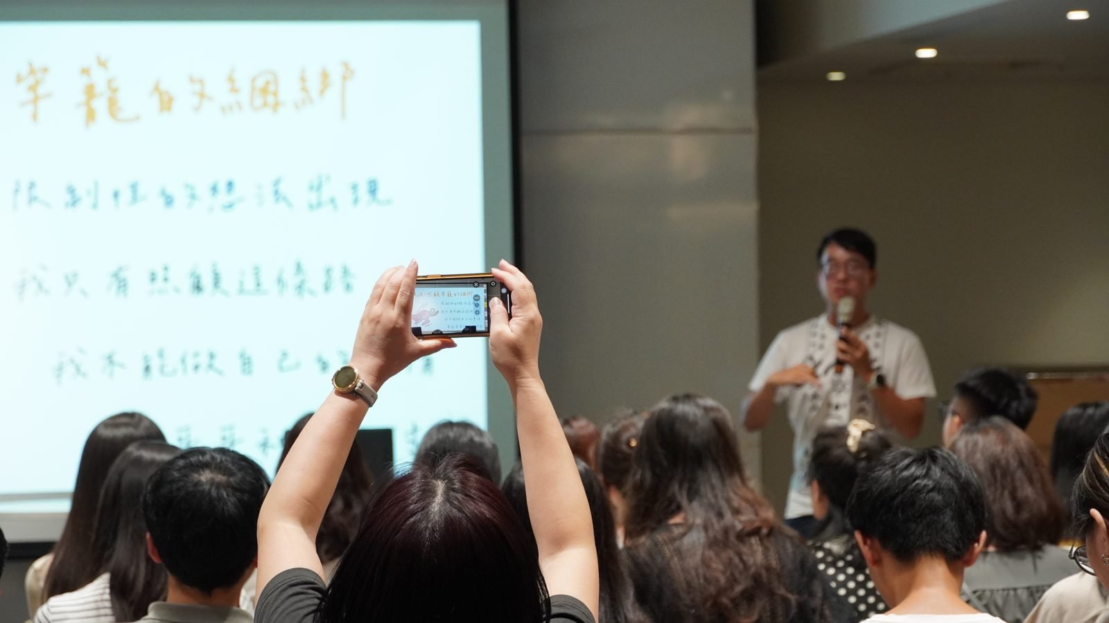 《認識年輕照顧者》講座現場，講者分享時參與者舉起手機記錄