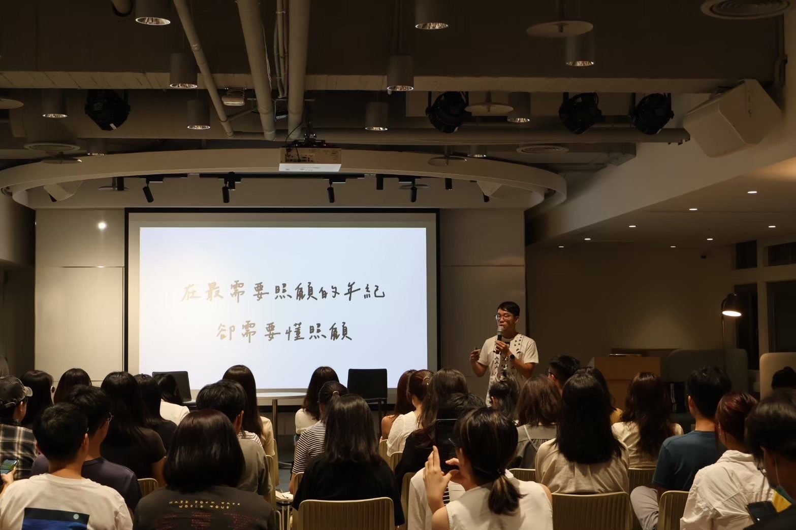 講者於台上分享，台下聽眾專注聆聽
