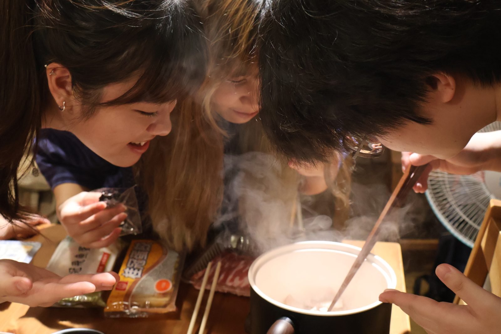 參與者圍著冒著熱氣的湯鍋一起料理